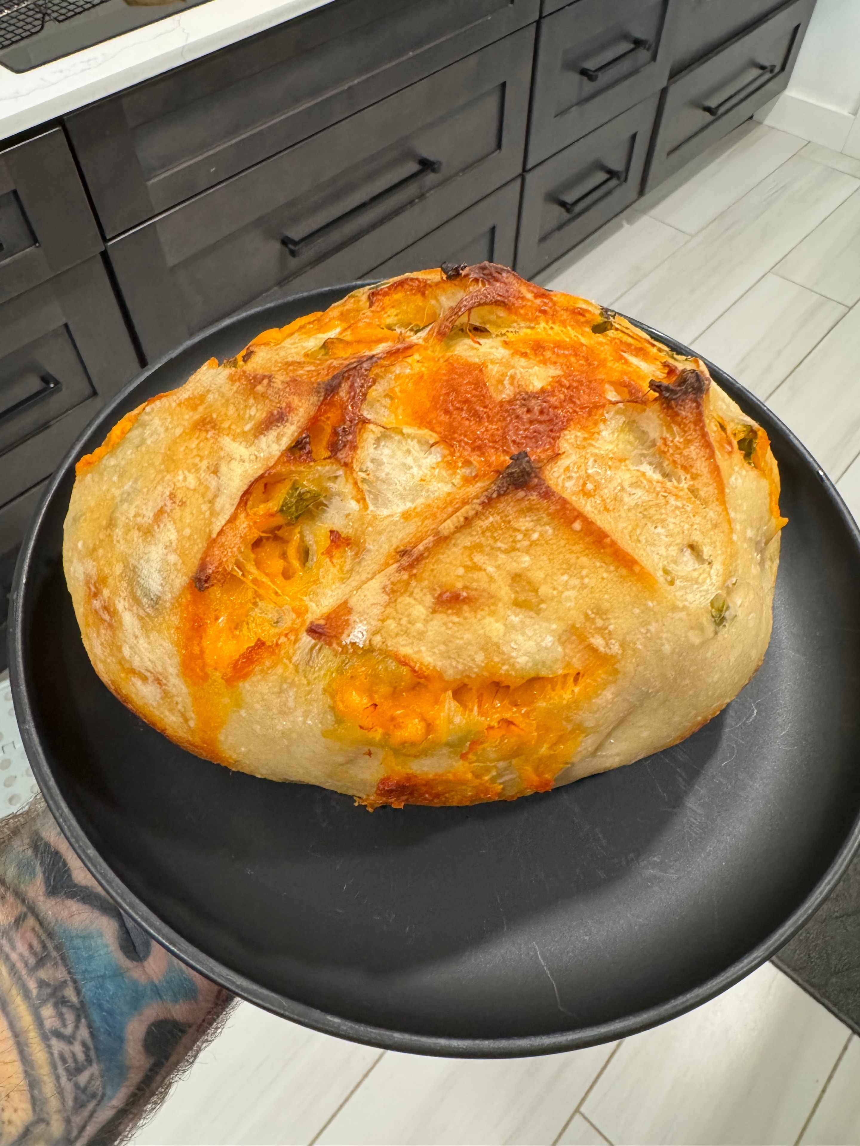 Cheddar jalapeño sourdough loaf in a black pan